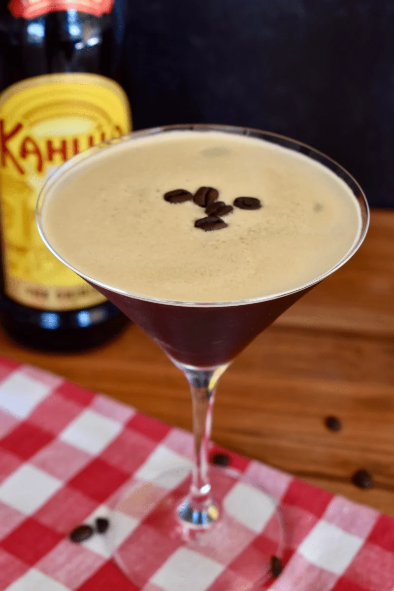 Espresso Martini with Kahlua in a martini class with a bottle of Kahlua in the background. 