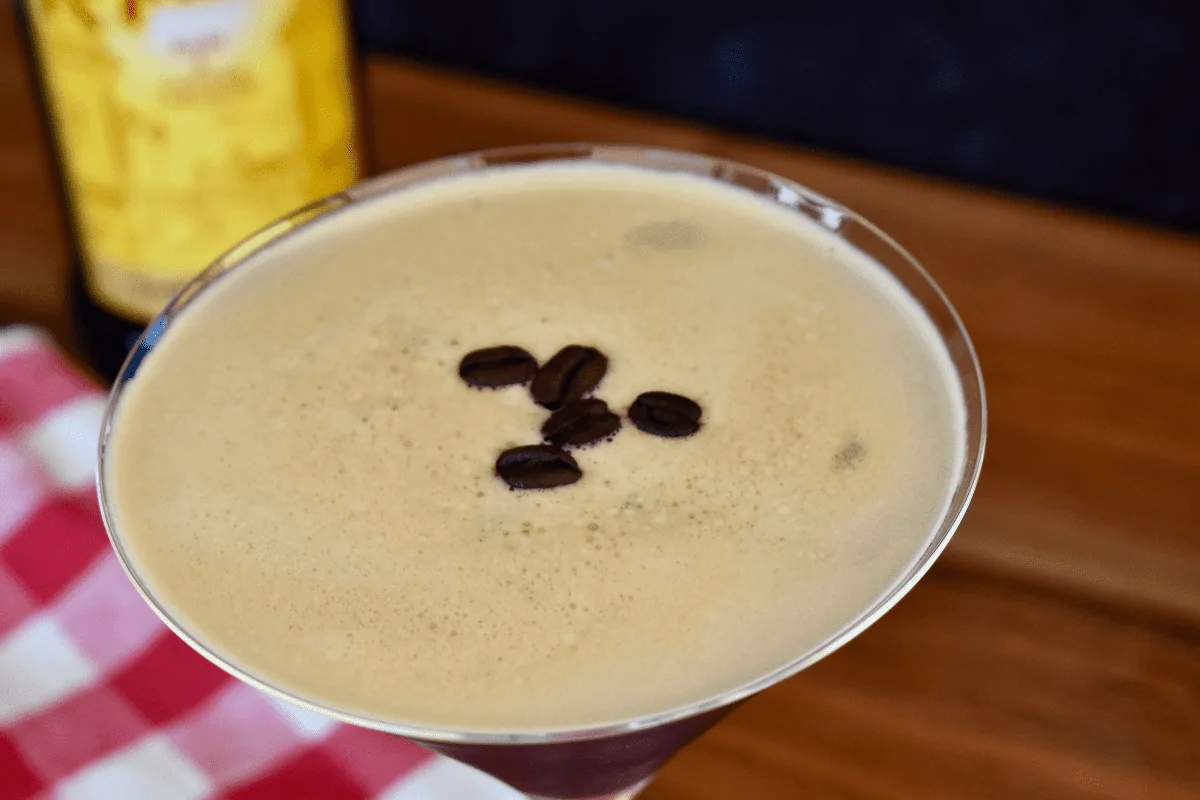 close up of foamy top of an espresso martini with espresso beans place on top. 