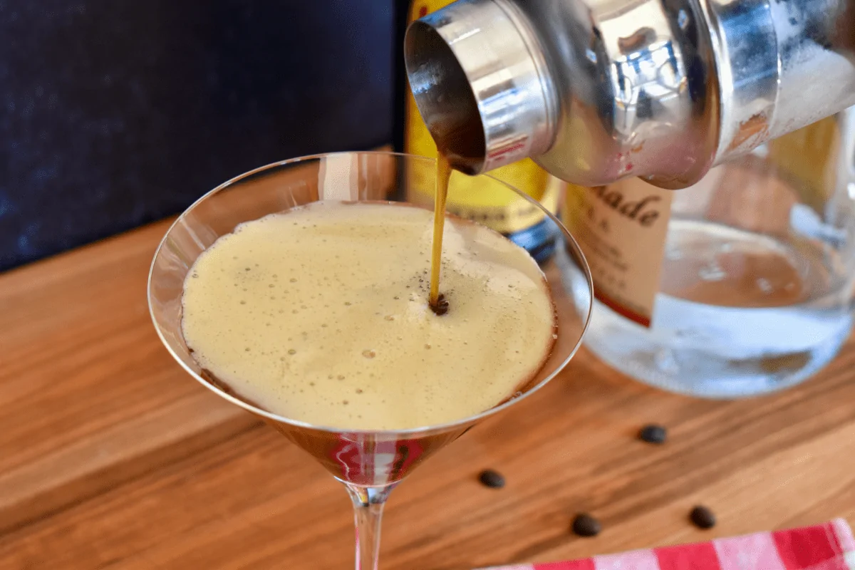 espresso martini with Kahlua being poured from cocktail shaker into martini glass.