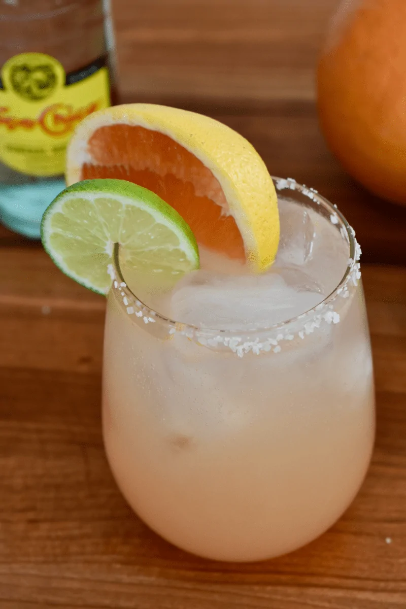 Grapefruit Paloma on a countertop with grapefruit slices on the side. 