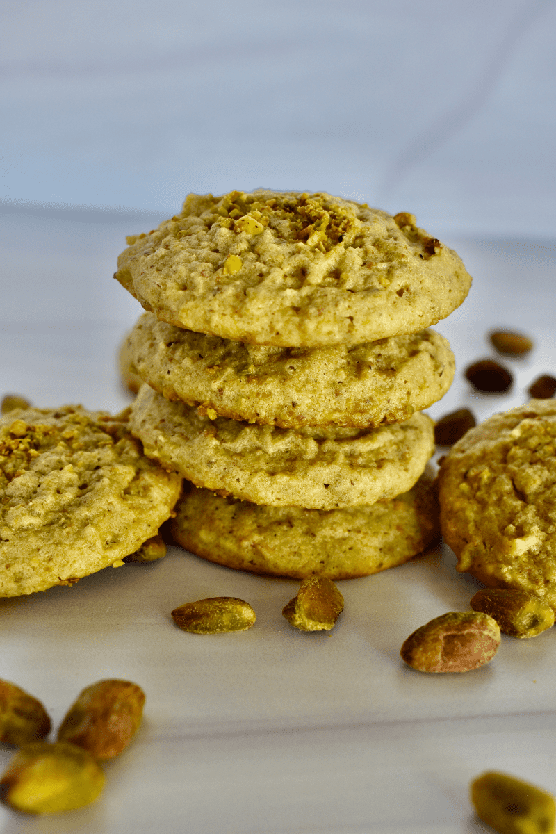 Italian Pistachio Cookies piled on top of each other on a white countertop. 
