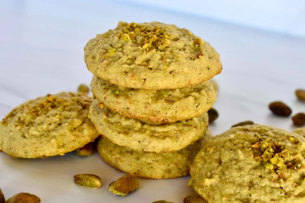 Pistachio cookies stacked on each other on a countertop. 