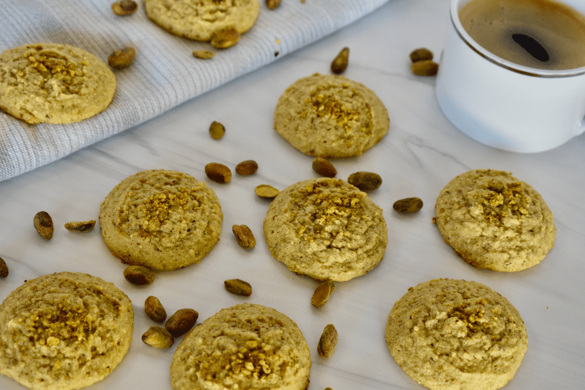 Italian Pistachio Cookies on a white countertop with pistachios scattered around them. 