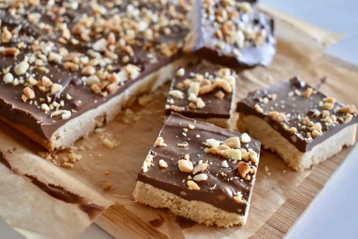 peanut butter shortbread bars on a cutting board with crushed peanuts on top.