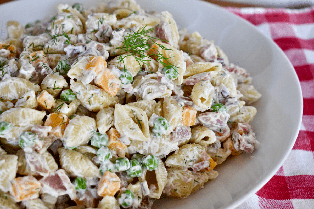 Ham Pasta Salad in a white bowl with a checkered napkin under it. 