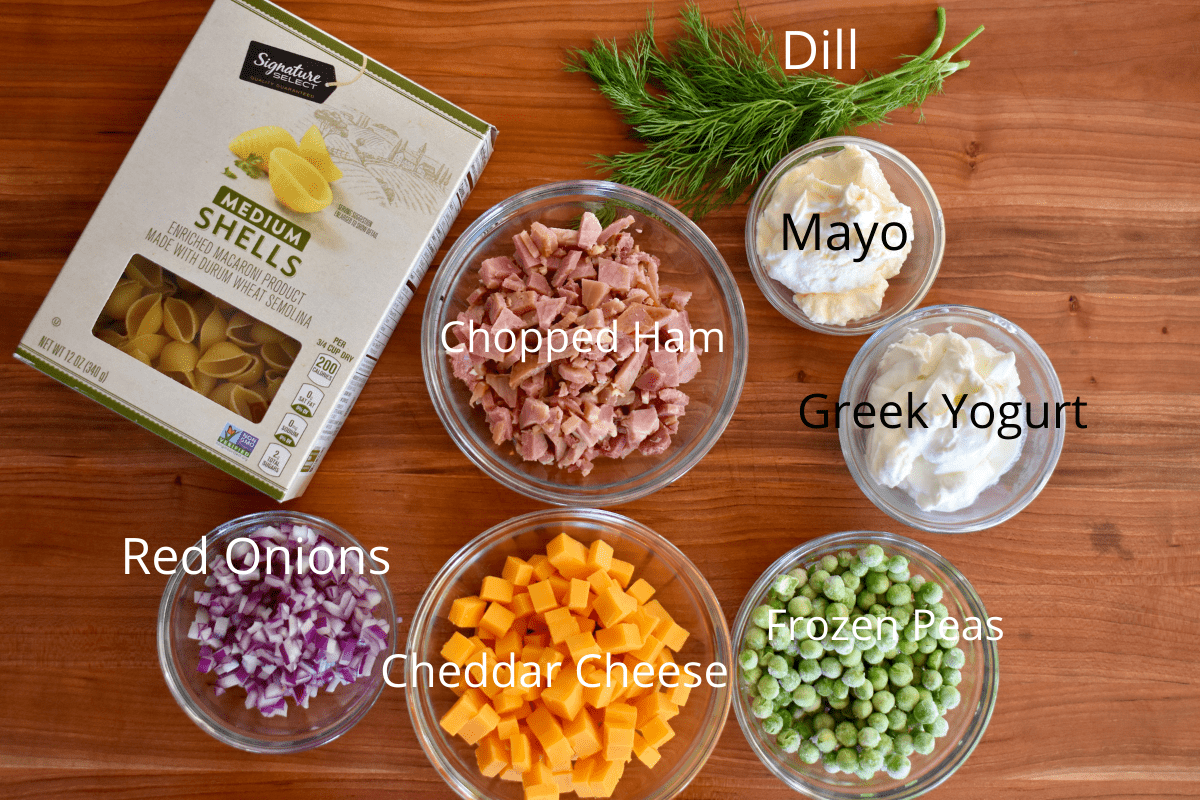 overhead photo of the ingredients including cheddar cheese, frozen peas, red onion, greek yogurt, dill, and mayo. 