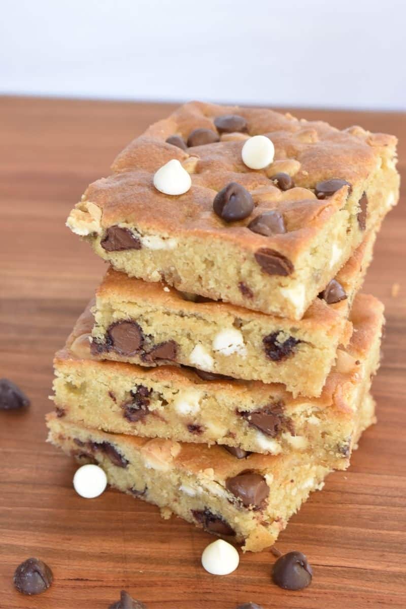 Sheet Pan Cookie Bars stacked on each other on a wood cutting board. 