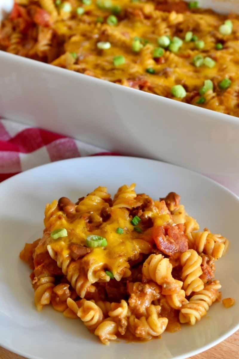Chili Pasta Bake on a white plate with a casserole dish behind it. 