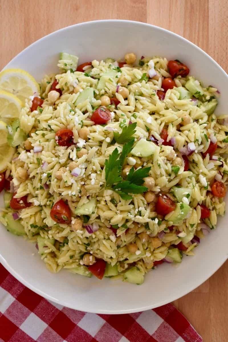 Lemon Orzo Salad on a white plate with a checkered napkin underneath it. 