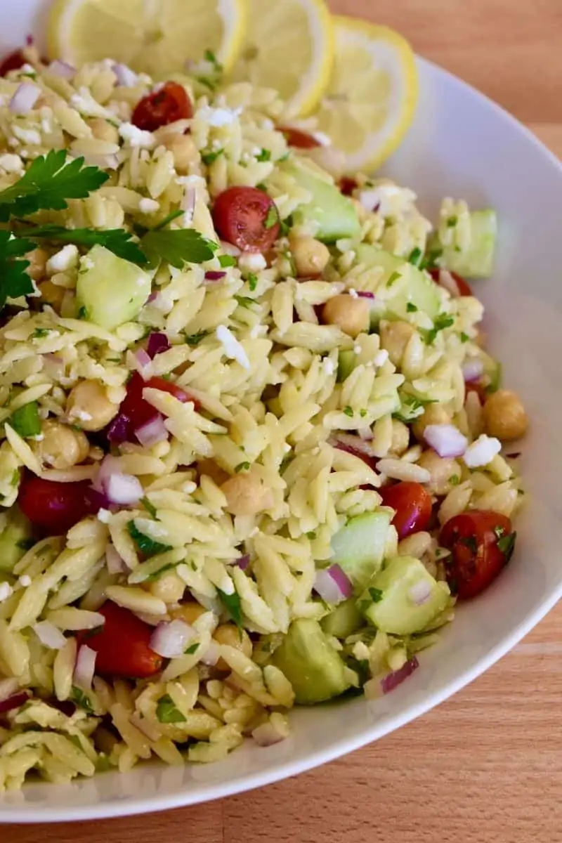 Lemon Orzo Salad in a bowl with cucumbers, tomatoes, parsley, lemon, garbanzo beans and feta. 