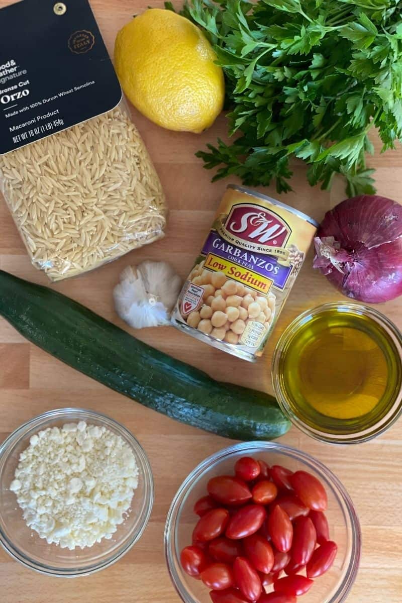 overhead photo of ingredients needed for recipe including garbanzo beans, feta, olive oil, tomatoes, cucumber, parsley, and red onion. 