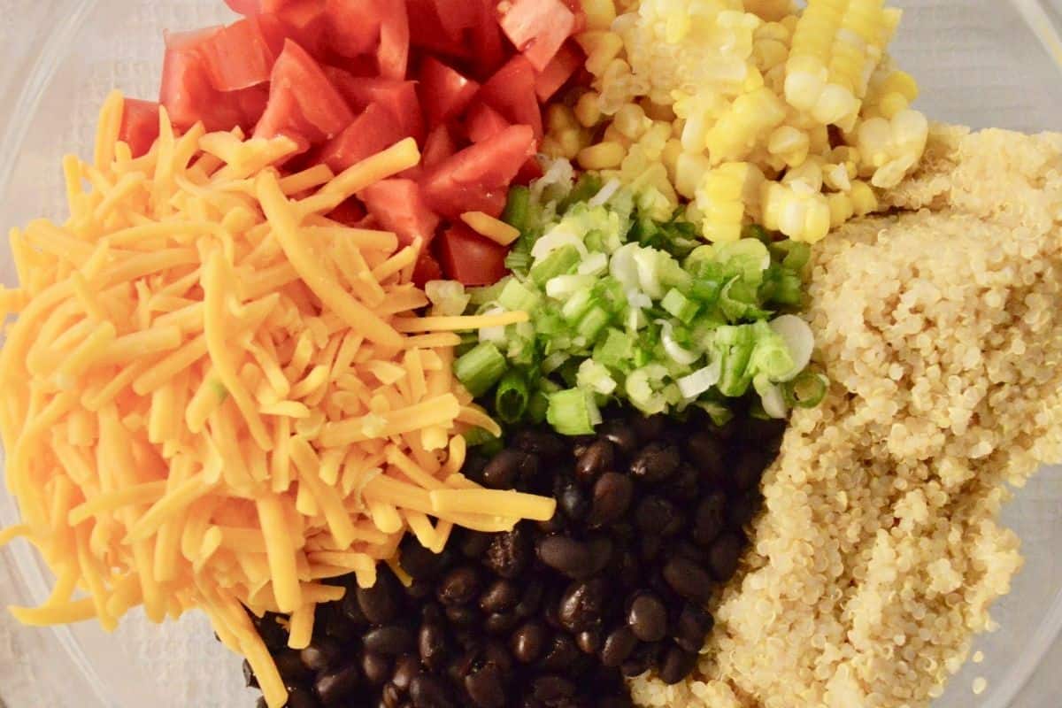 overhead photo of ingredients in a glass bowl including tomatoes, black beans, corn, and onions. 