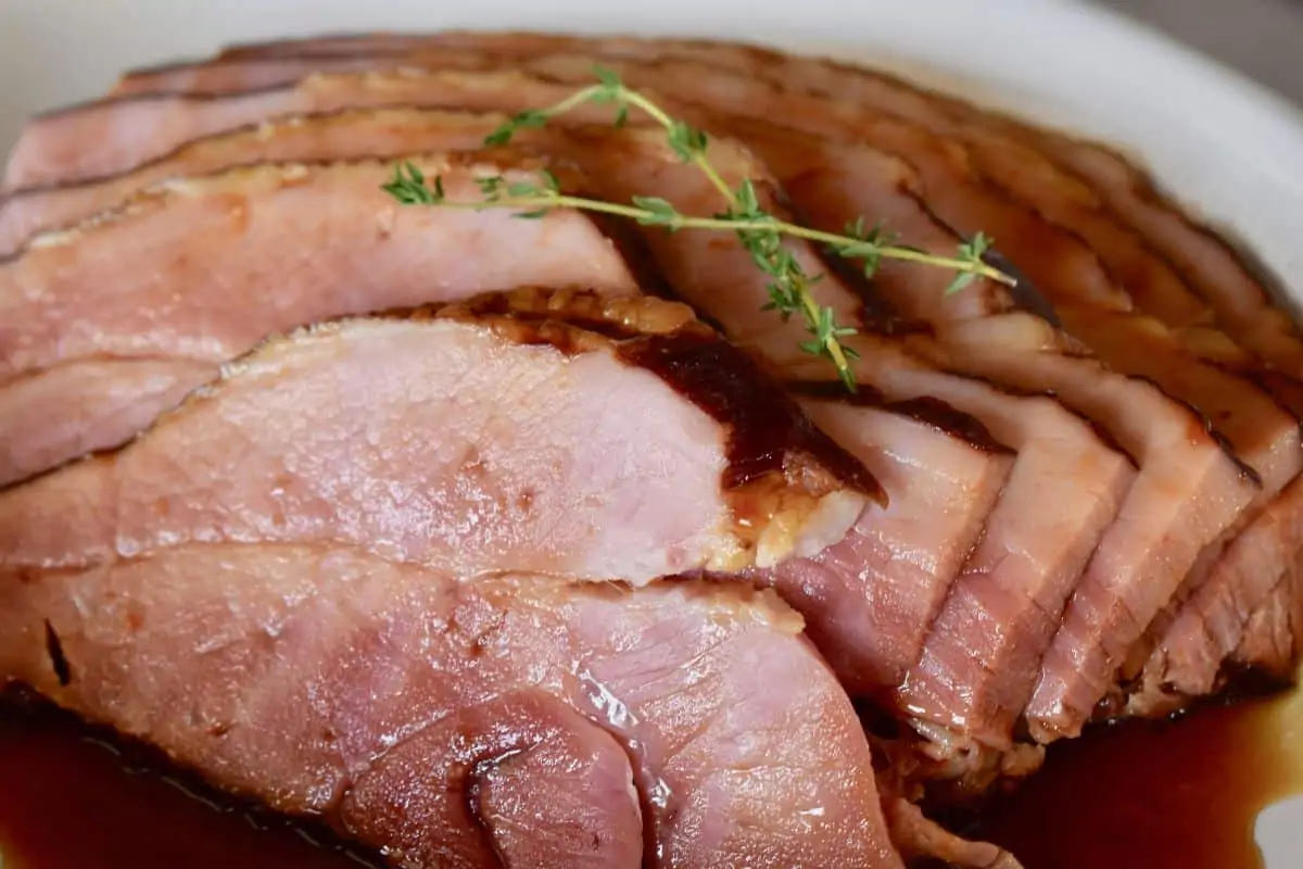 Slow cooker ham on a plate with brown sugar glaze poured overtop. 