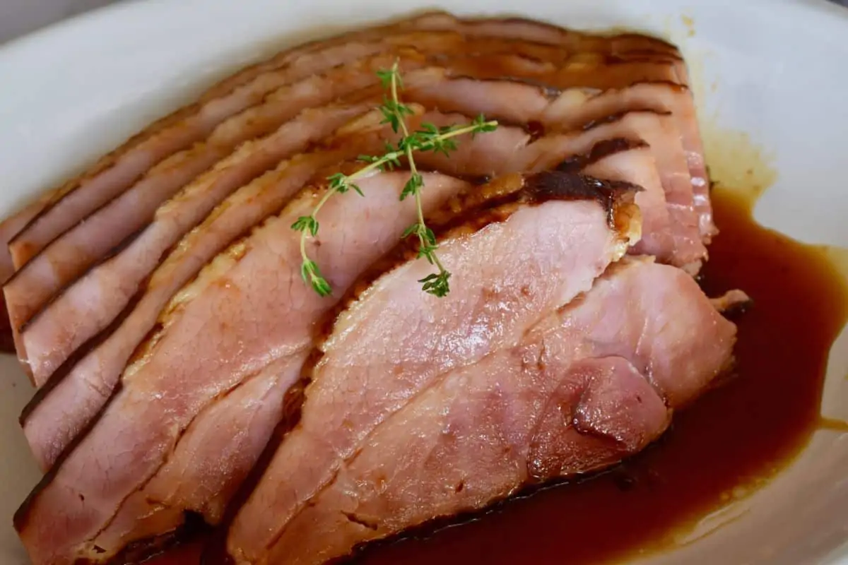 Slow Cooker Ham on a white plate with a brown sugar glaze poured over it. 