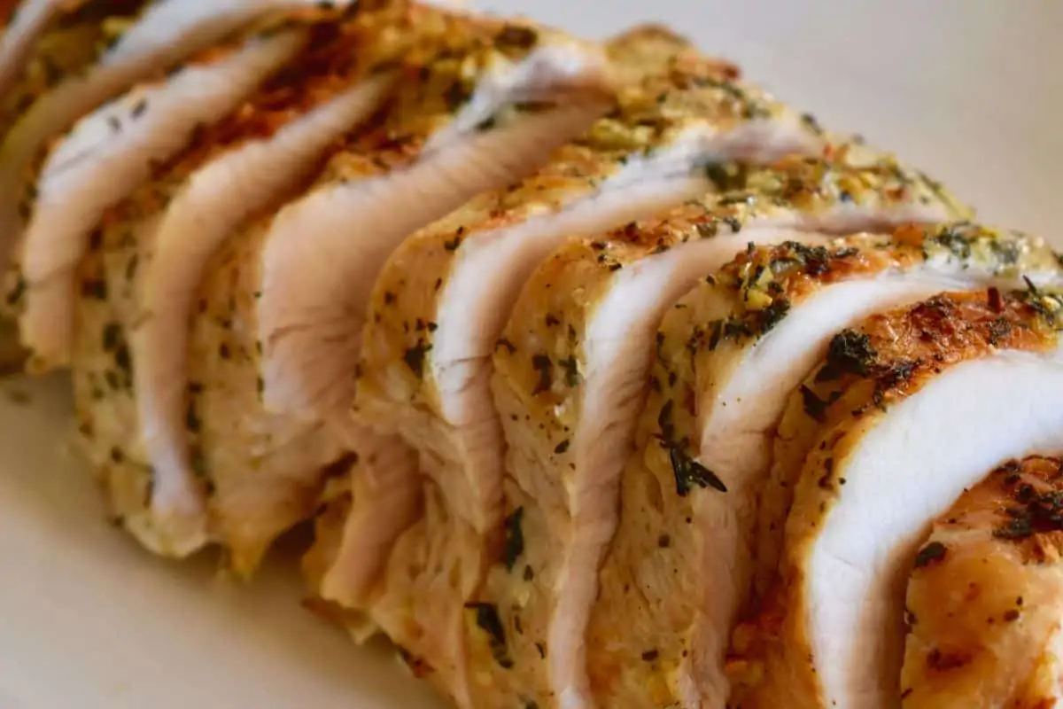 Slow Cooker turkey breast cut into slices on a white serving platter. 