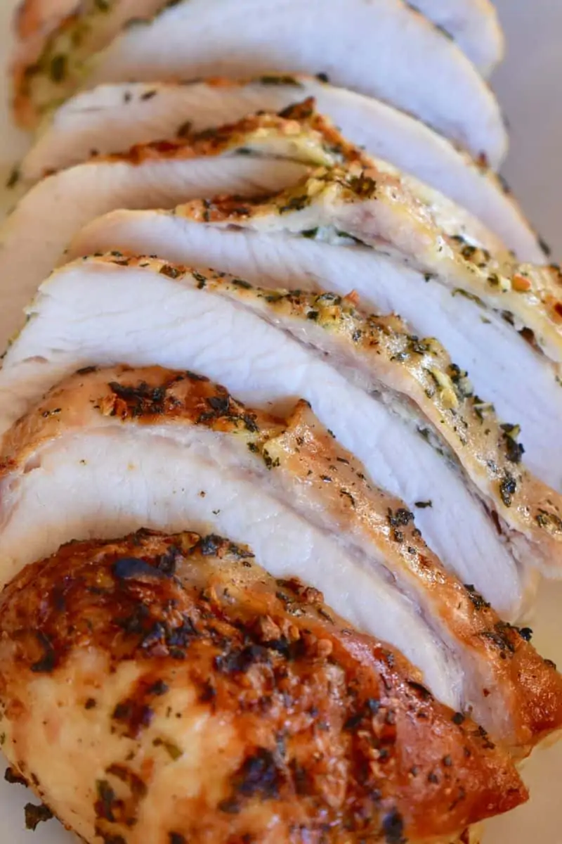 slow cooker turkey breast cut into slices on a white serving platter. 
