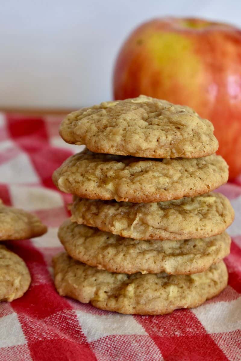 Apple Spice Cookies stacked on each other with an apple in the background. 