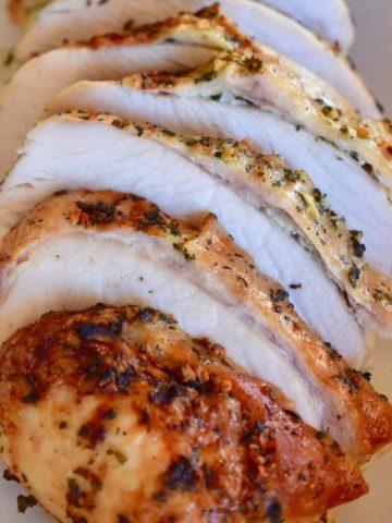 slow cooker turkey breast cut into slices on a white serving platter.