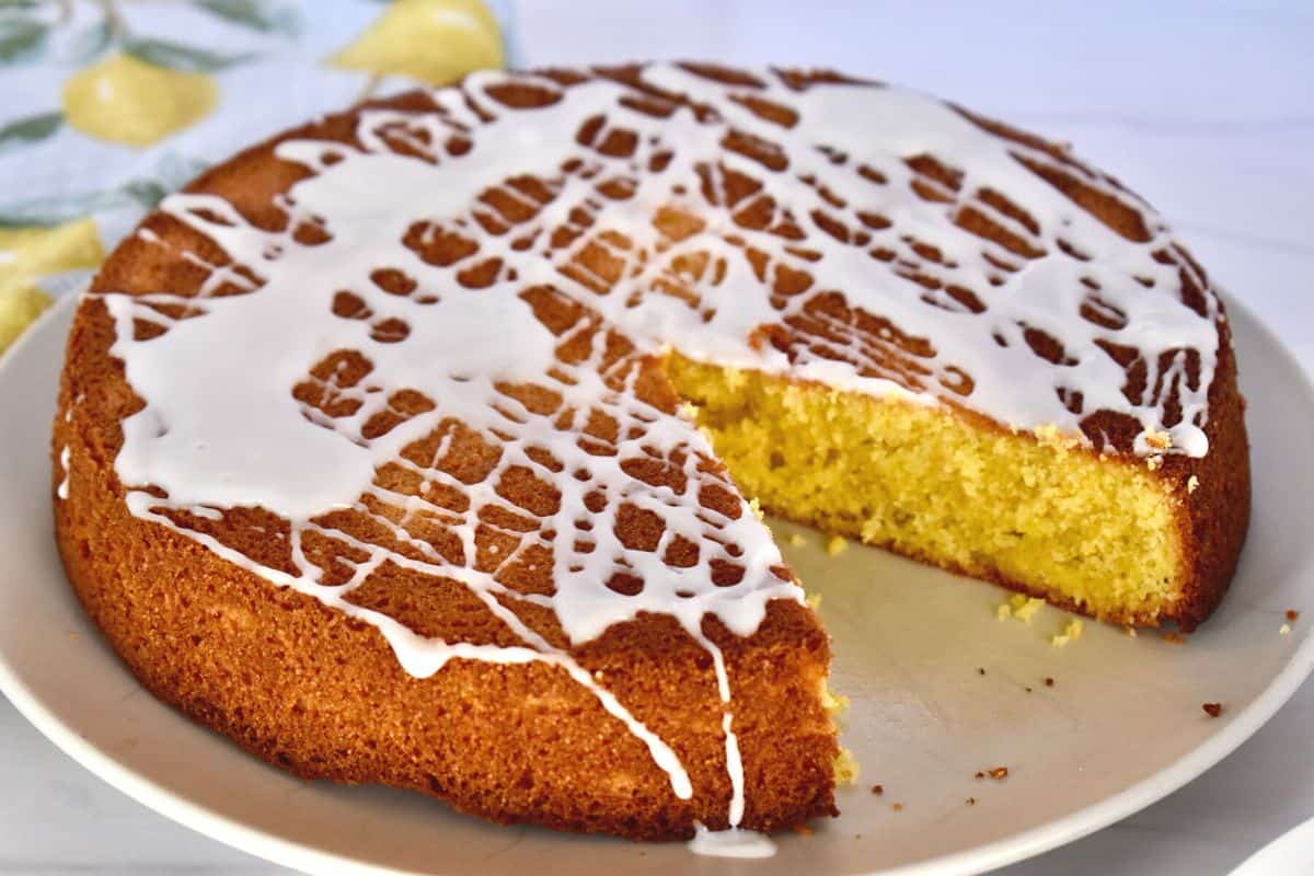 Lemon Polenta Cake with lemon glaze on a white plate. 