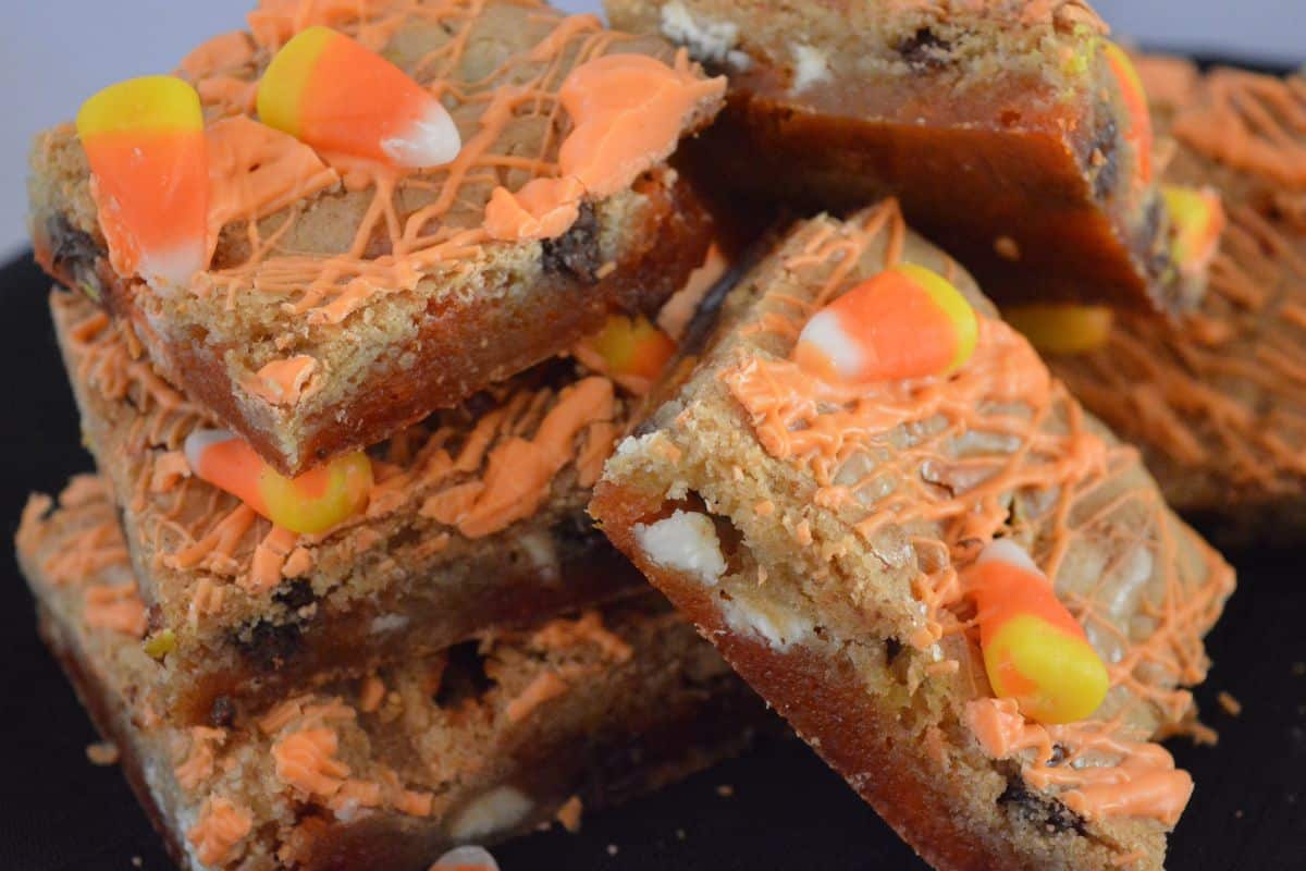 Candy Corn Halloween Blondies on a a black background piled on each other. 