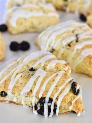 Cherry Scones with almond glaze on a white countertop with dried cherries around them.