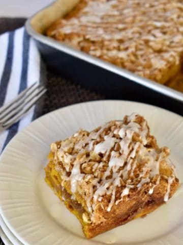Pumpkin Streusel Coffee Cake on a plate with a pan of cake in the background.