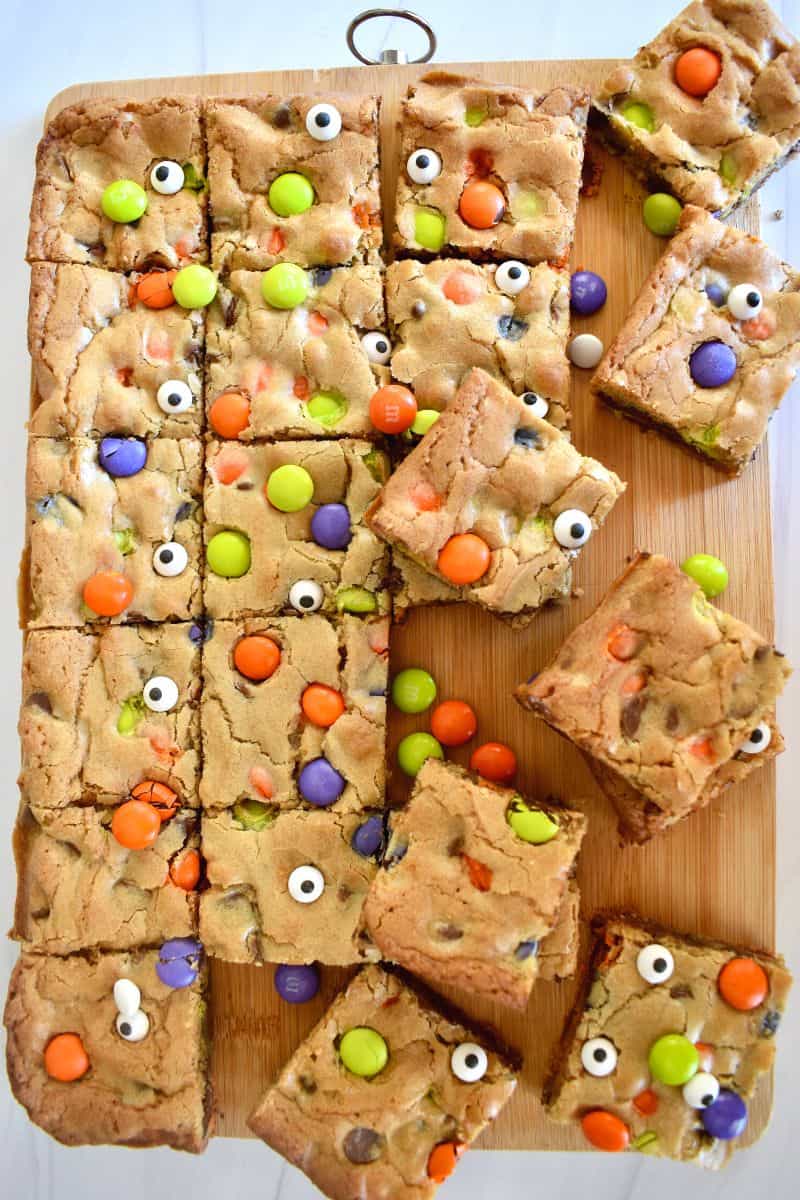 Halloween Cookie Bars cut into squares on a wood cutting board. 