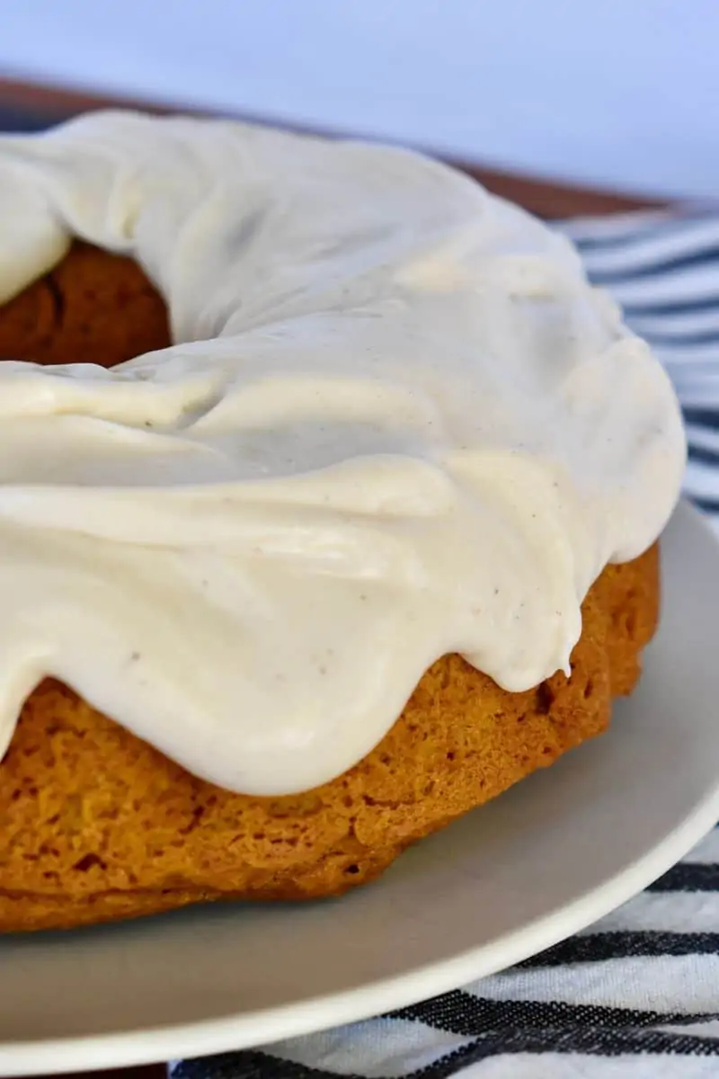 Pumpkin Bundt Cake with Cream cheese frosting on a white plate. 