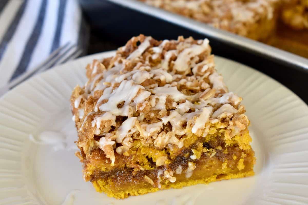 Slice of pumpkin streusel coffee cake on a stack of white plates. 