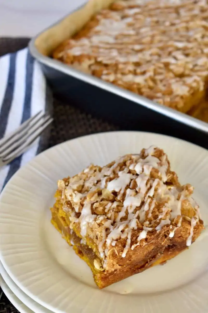 Pumpkin Streusel Coffee Cake on a plate with a pan of cake in the background. 