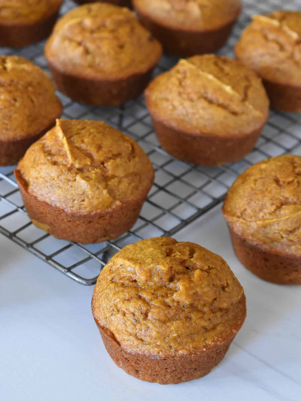 Pumpkin applesauce muffins on a cooling rack. 