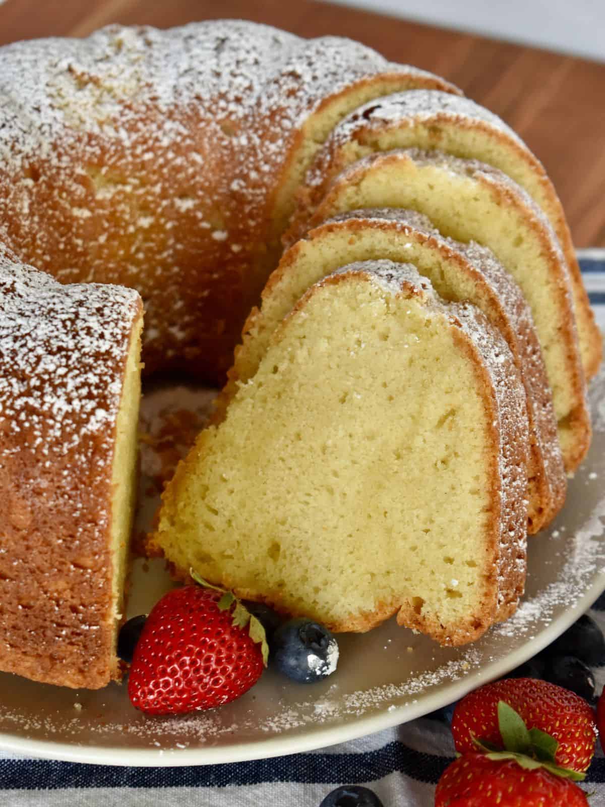Sour Cream Pound Cake sliced on a plate with berries and powdered sugar. 