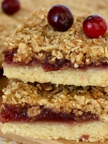 Cranberry Shortbread Bars stacked on each other with fresh cranberries on top.