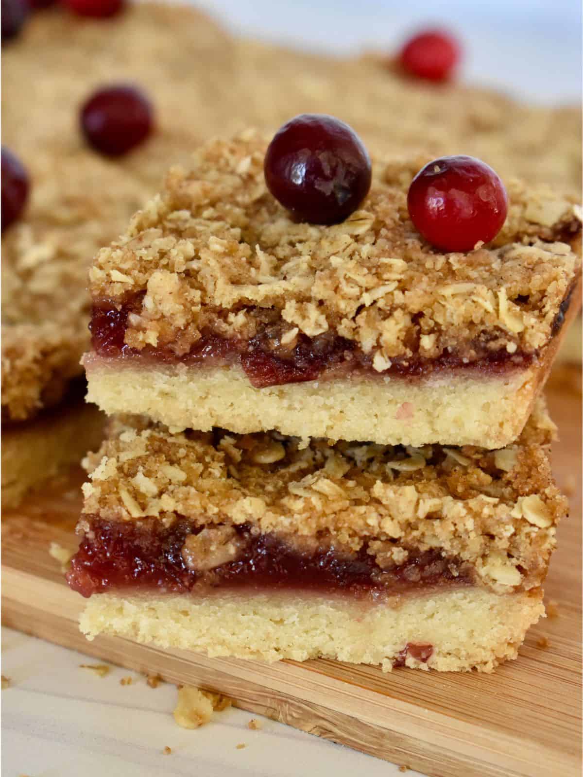 Cranberry Shortbread Bars stacked on each other with fresh cranberries on top. 