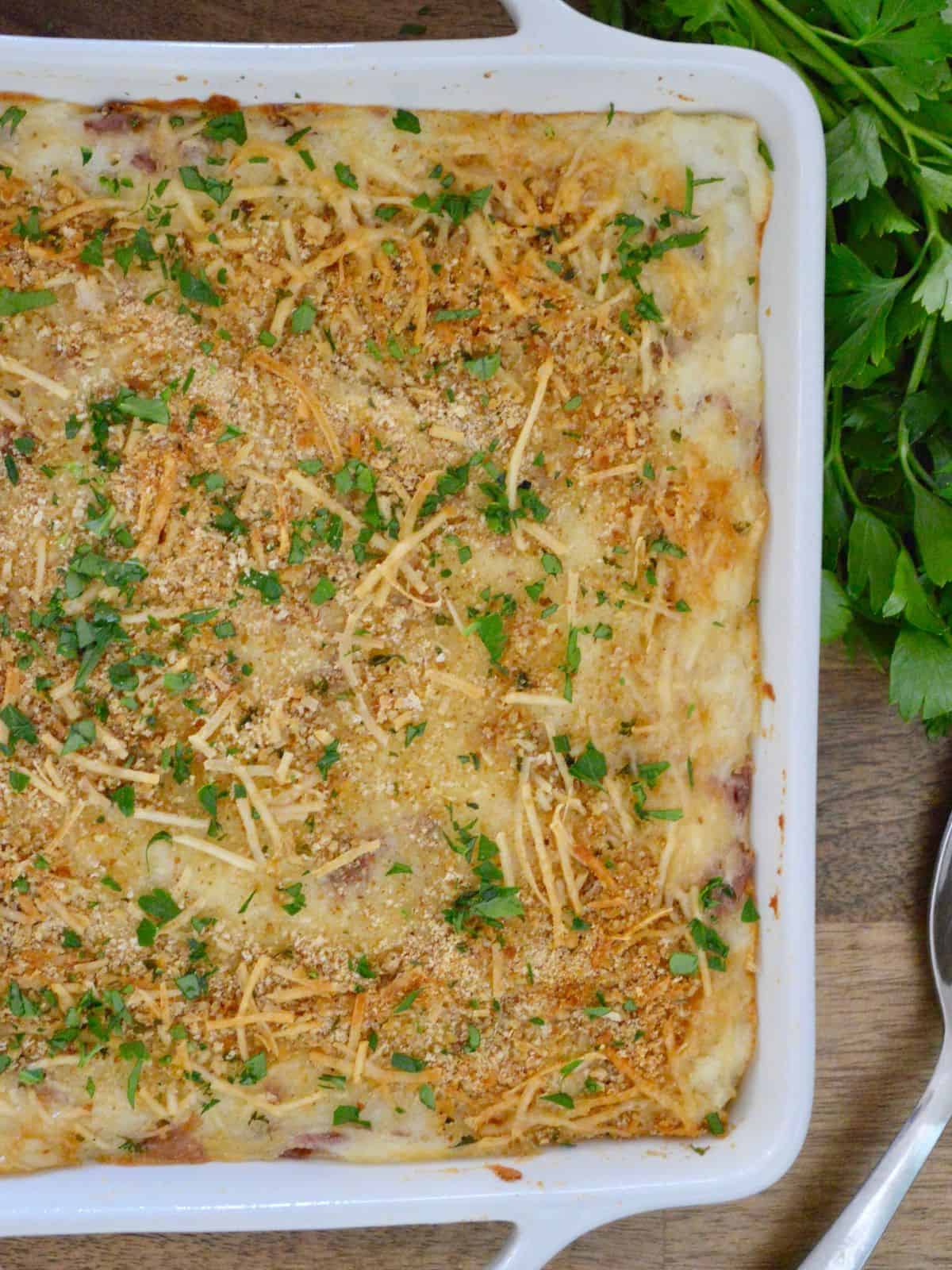 Italian Mashed potatoes in a white serving dish with parsley in the background. 