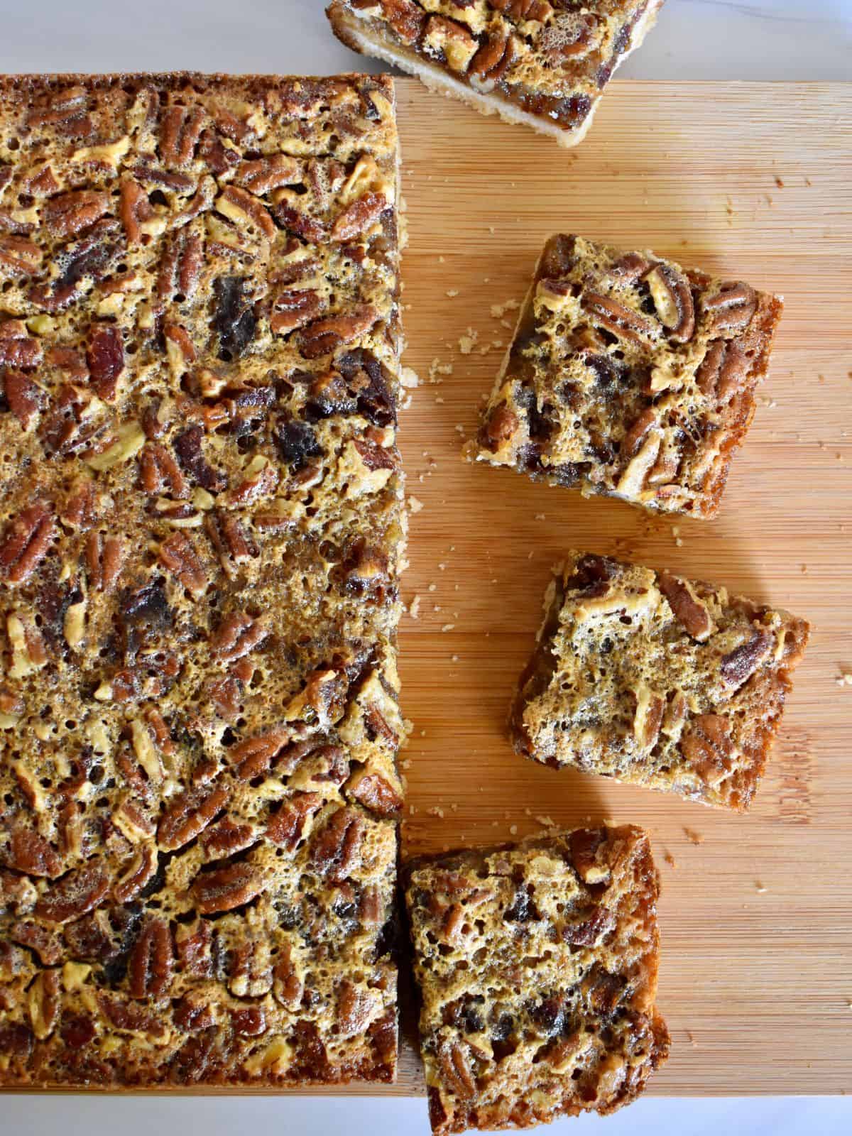 overhead photo of pecan pie date bars on a cutting board. 