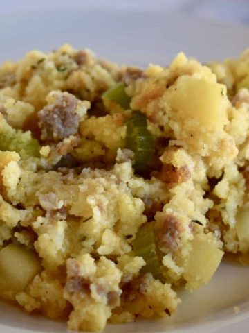 Cornbread stuffing with sausage and apple on a white plate.