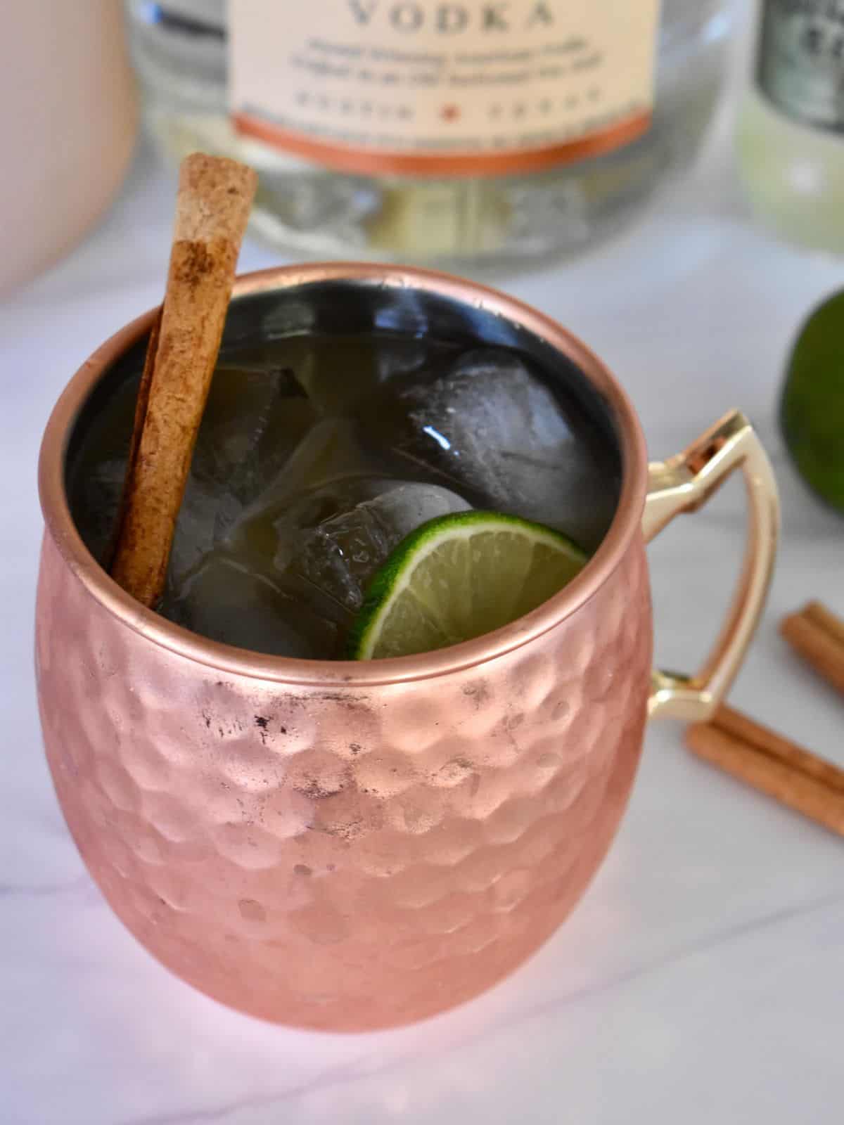 Apple Cider Moscow Mule in a cooper mug with a cinnamon stick. 