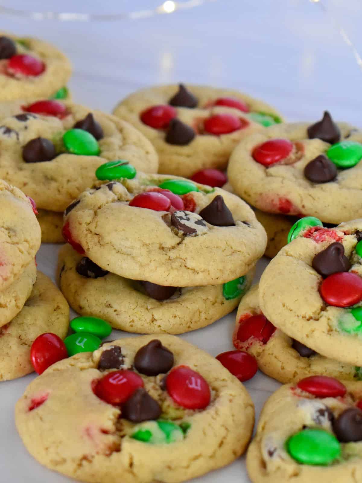 Christmas M&M Cookies on a white surface with chocolate chips.