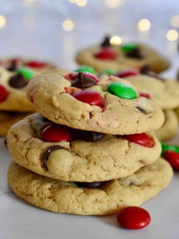 Christmas M&M cookies stacked on each other on a white countertop.