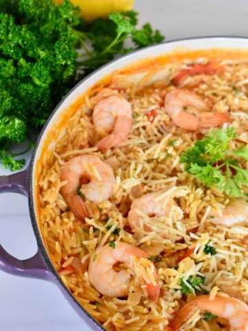 overhead photo of shrimp orzo in a large pot with parsley next to it.