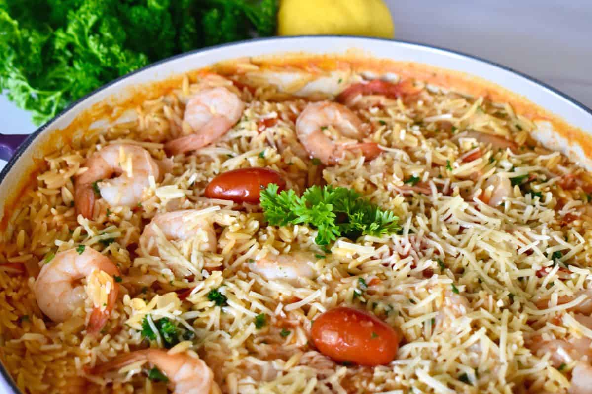 Shrimp Orzo in a pot with parsley and cherry tomatoes on top. 