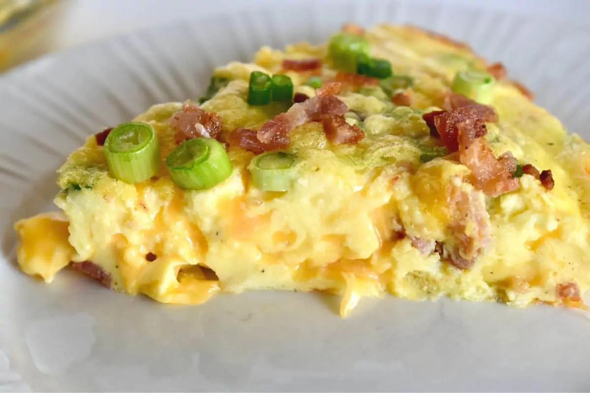 Cottage Cheese Quiche on a white plate topped with bacon and green onions. 