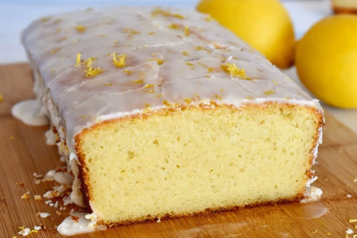 Lemon Ricotta Pound Cake on a cutting board with lemons in the background. 