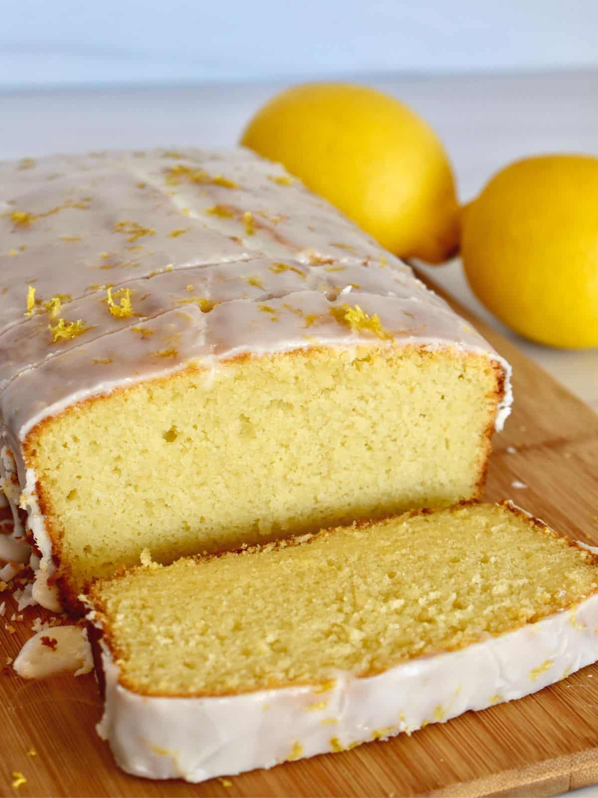 Lemon Ricotta Pound Cake on a wood cutting board with a slice in front of it and lemons in the background. 