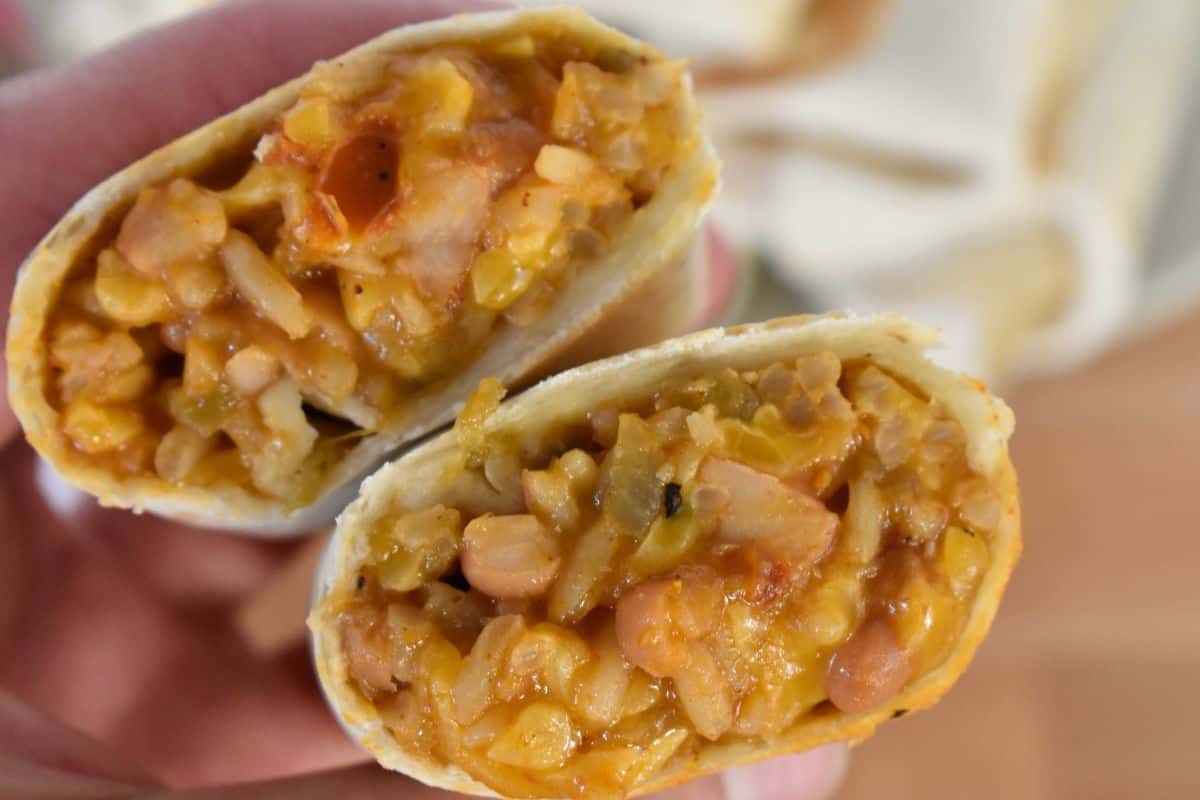 Filling of a cheesy rice and bean burritos held in my hand. 