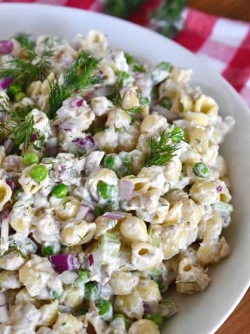 Tuna Pasta Salad with dill in a white bowl on a checkered napkin.