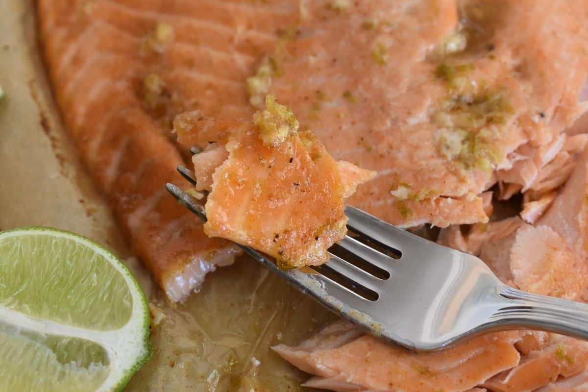 honey lime salmon on a fork with a slice of lime next to it. 