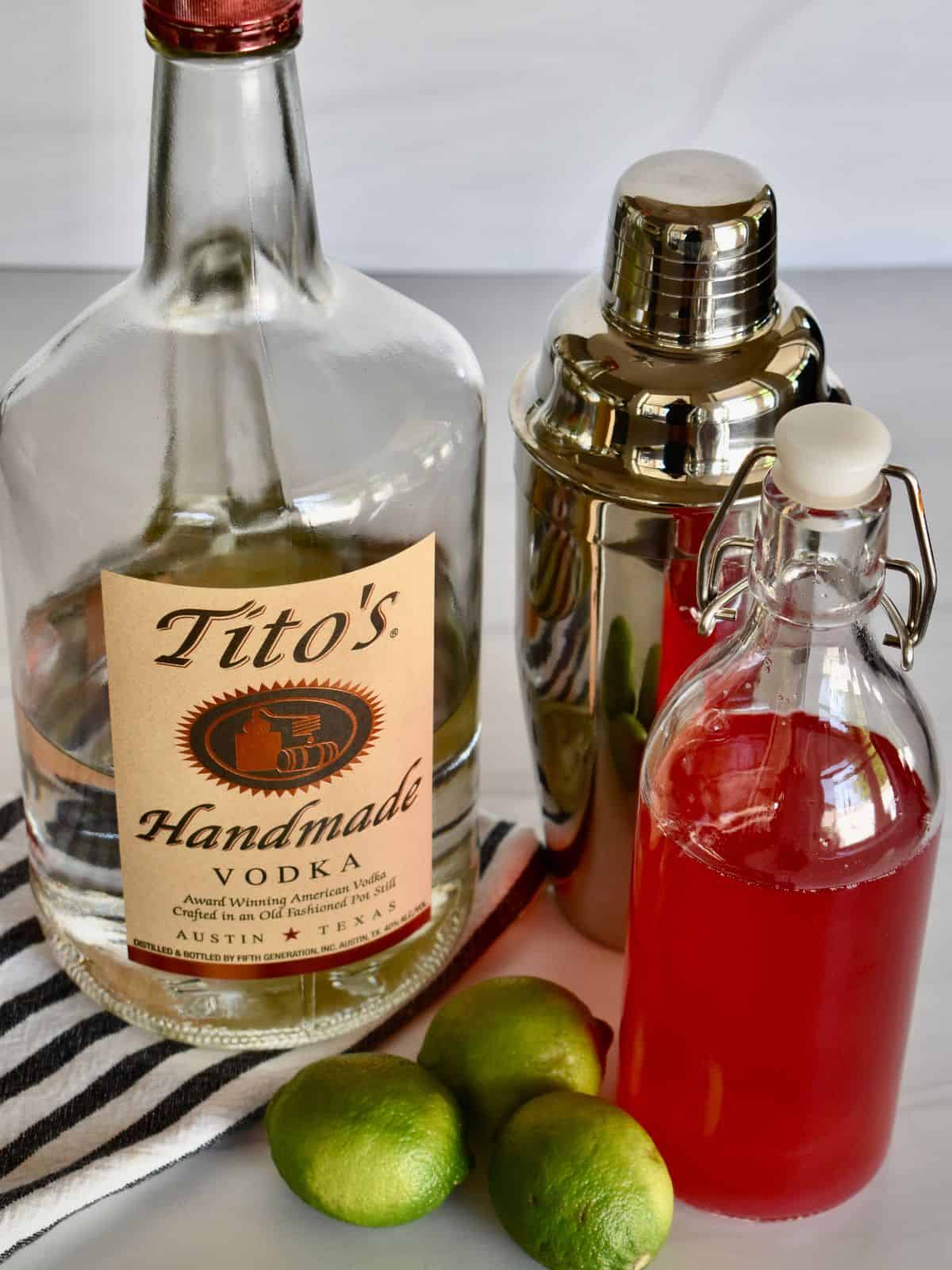 Ingredients needed to make recipe including infused simple syrup, Tito's vodka, and limes. 