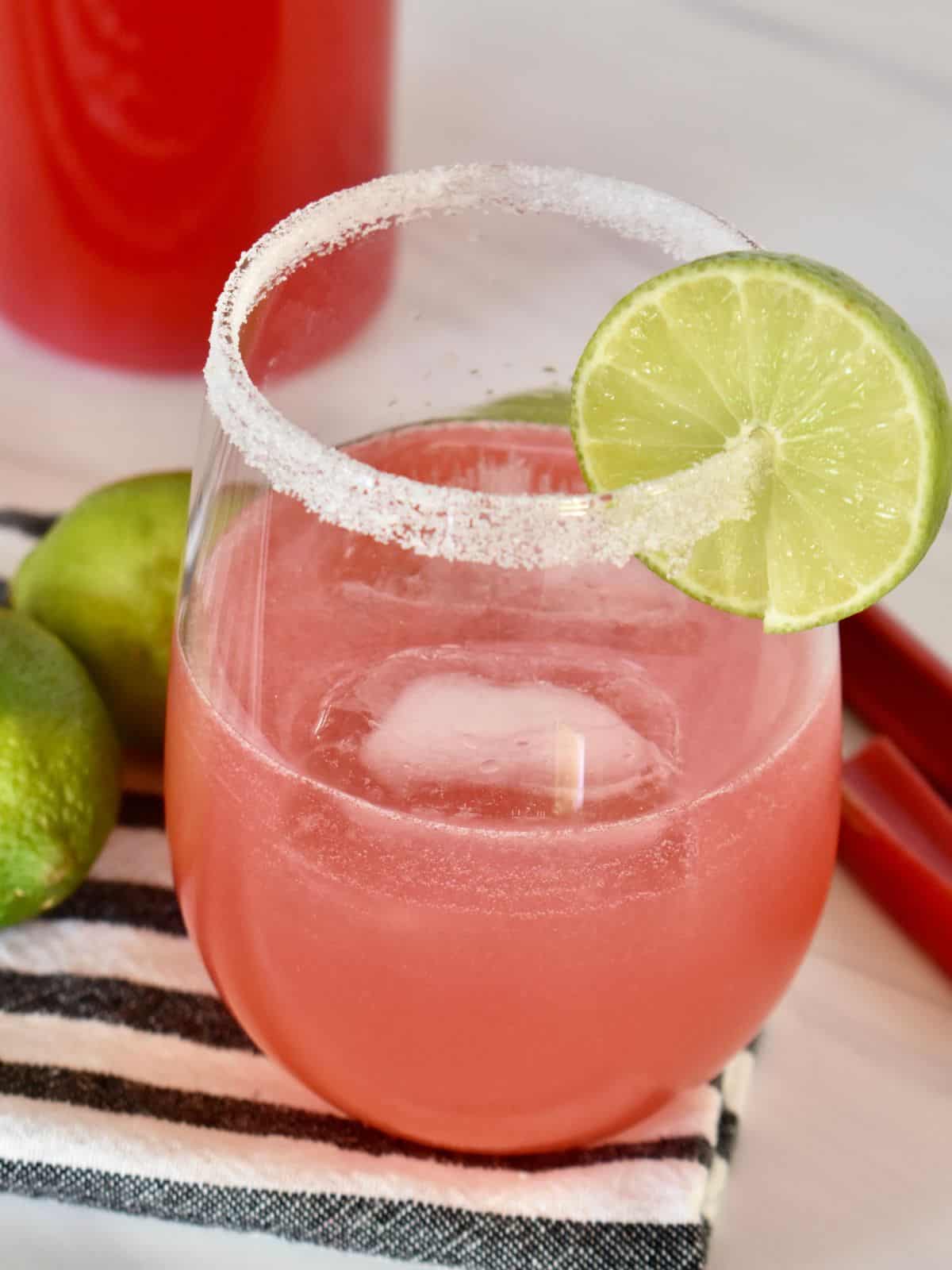 Rhubarb Cocktail in a glass with a sugared rim and slice of lime. 